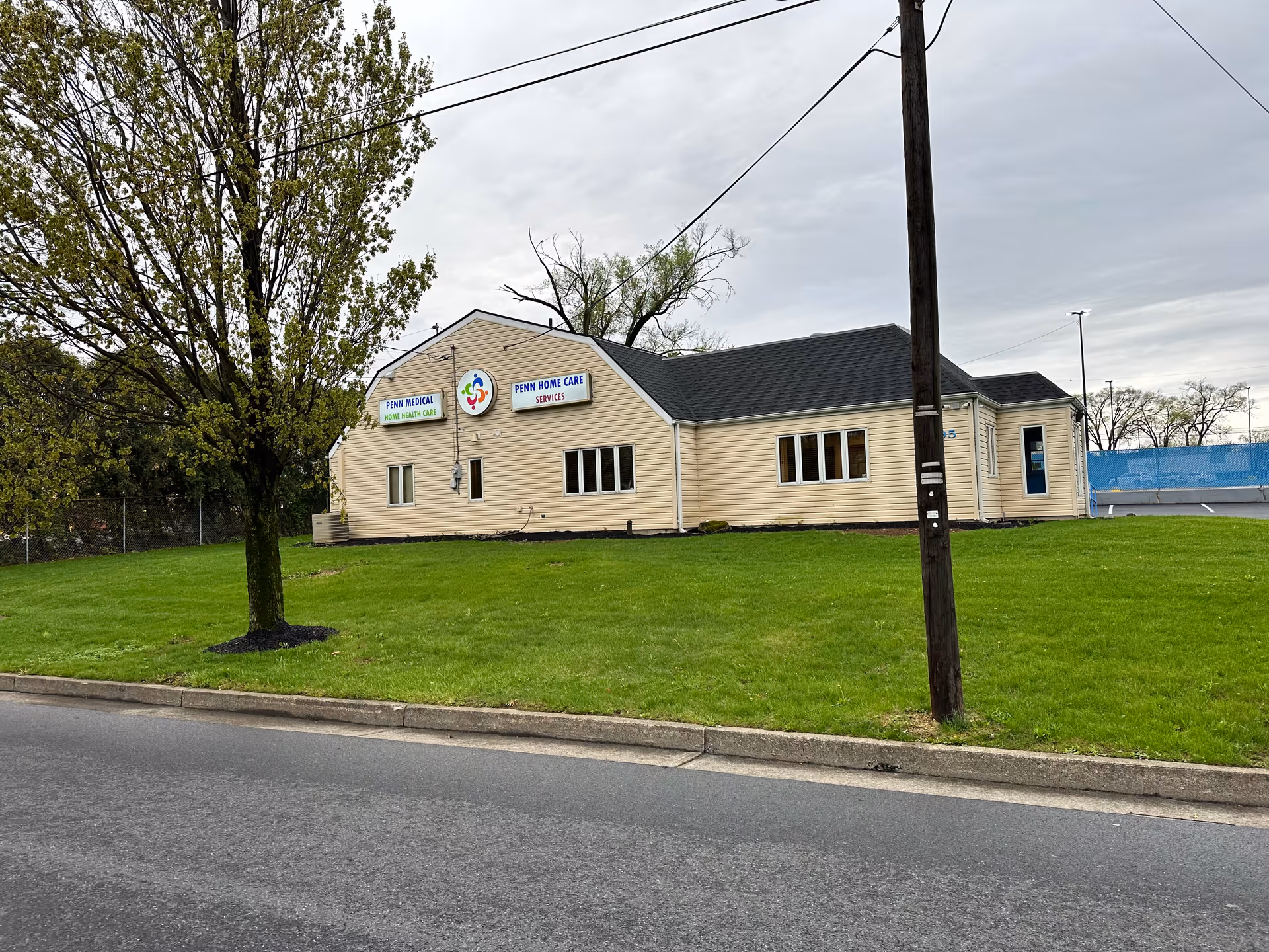 Single-story beige senior care facility with Penn Home Care signs on a grassy roadside lot.