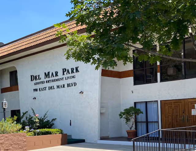 Front exterior of Del Mar Park assisted retirement living facility with sign.