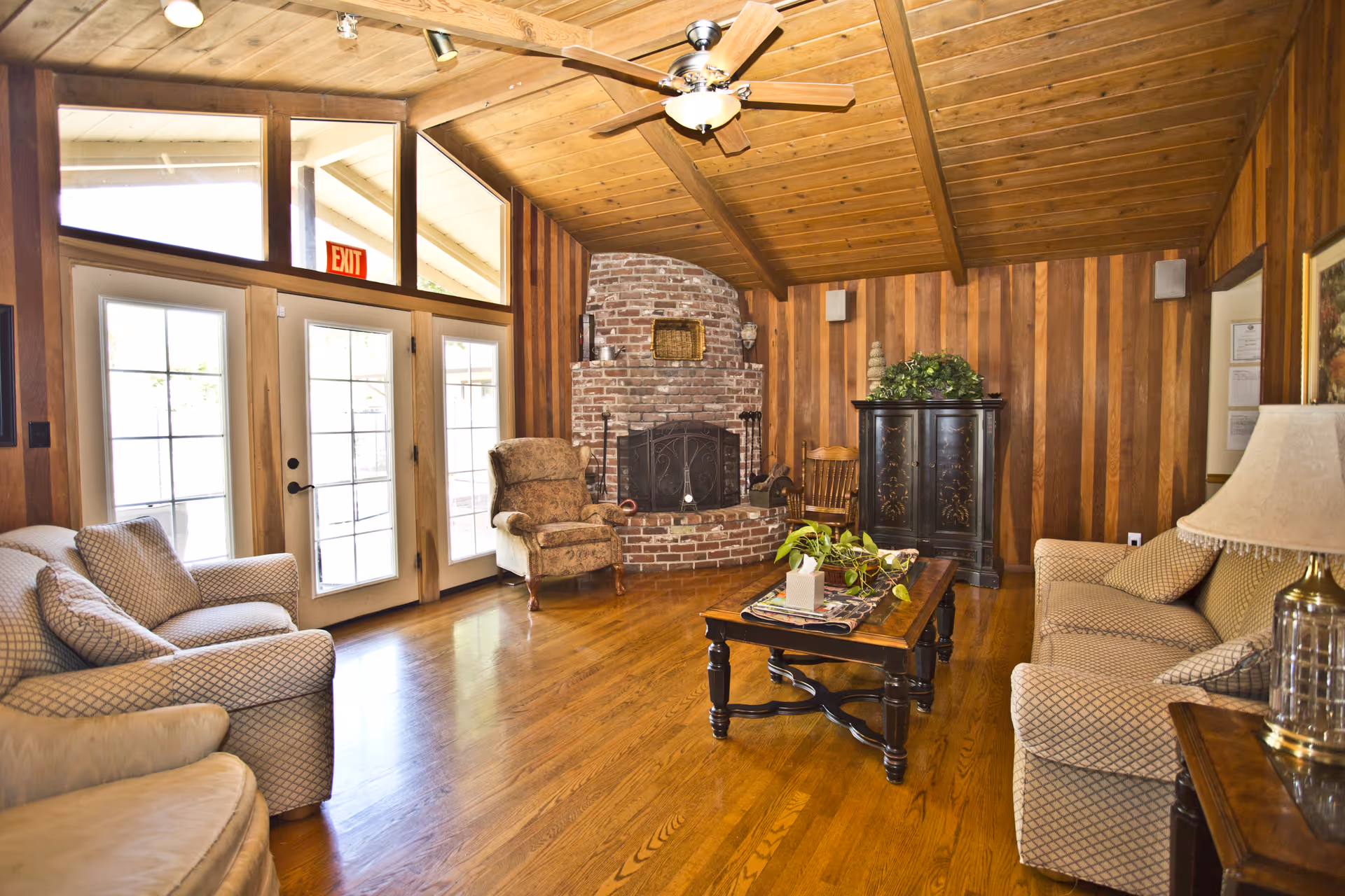 Wood-paneled living room with brick fireplace, couches, and coffee table.
