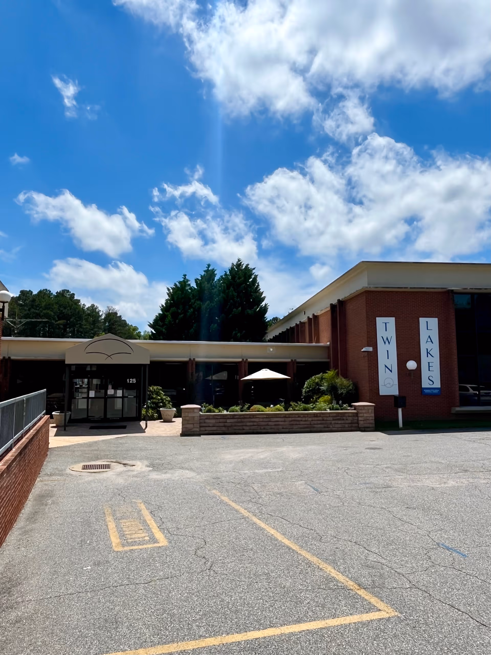 Exterior view of Twin Lakes Rehabilitation and Nursing facility, brick building, entrance, and parking lot.