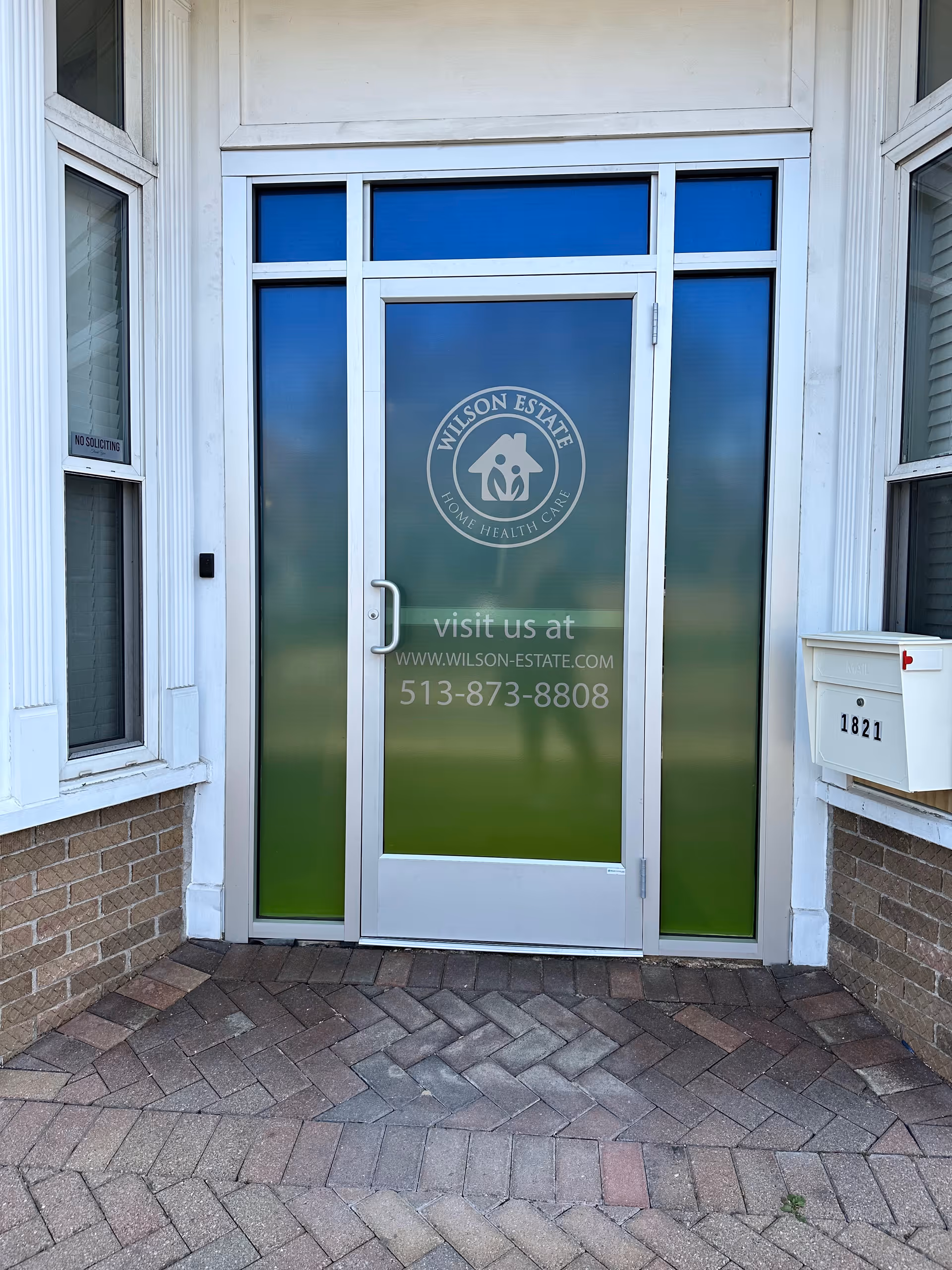 Entrance door to Wilson Estate facility with frosted glass and logo, framed by windows.