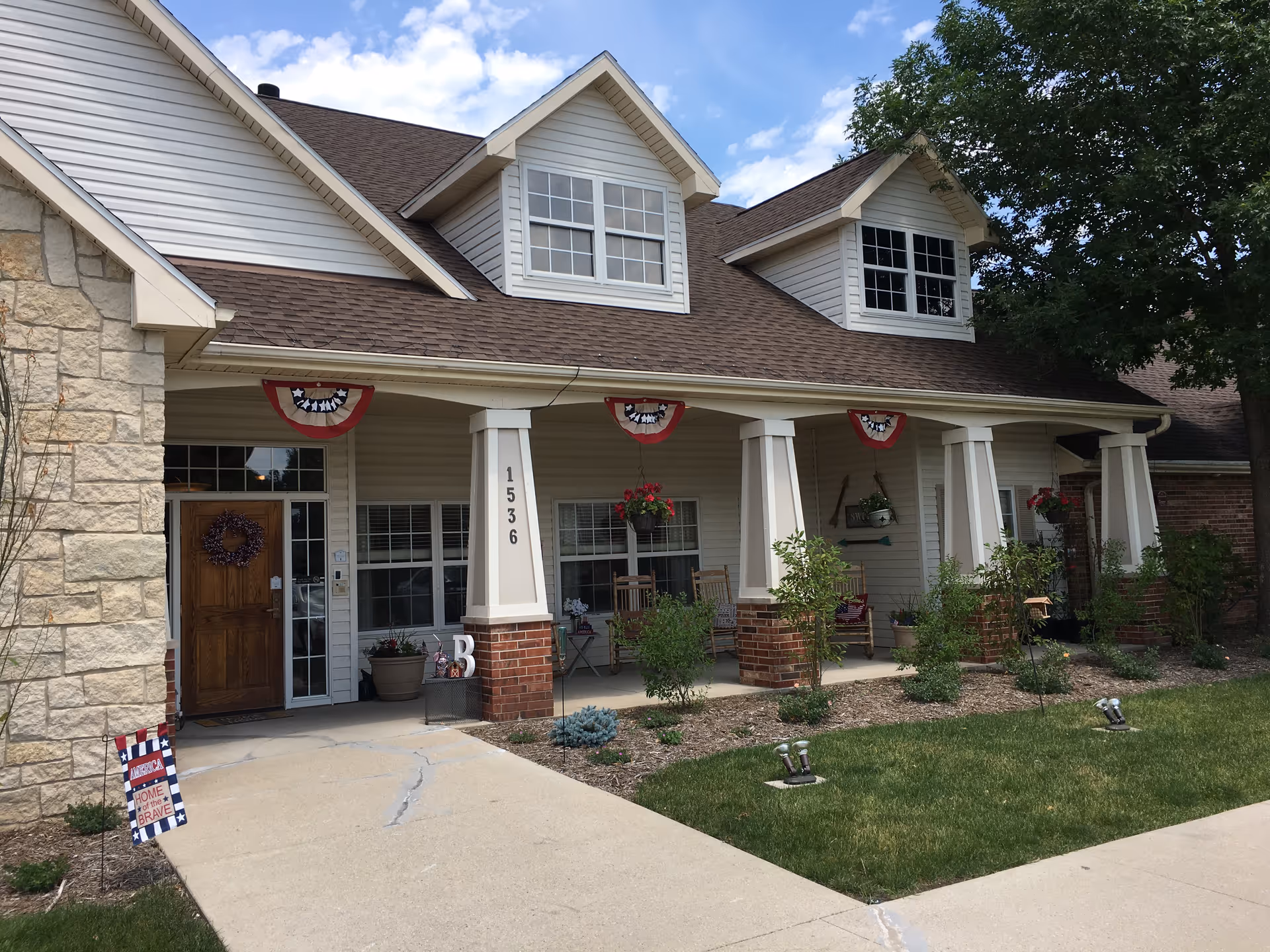 Front view of a senior living facility with a covered porch and patriotic decorations.