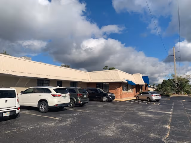 Exterior view of QwestCare Home Health facility with parked cars and blue awnings
