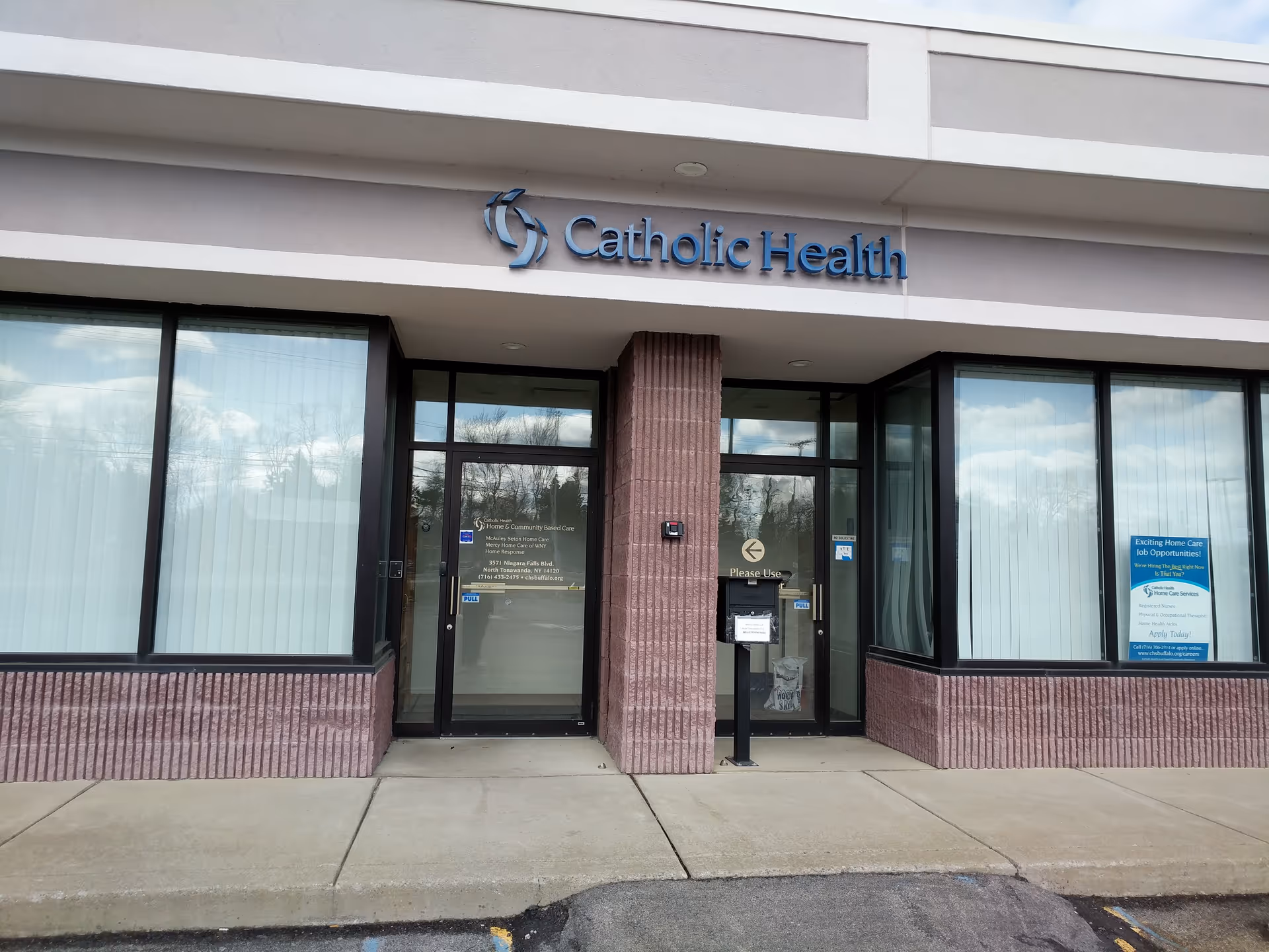 Exterior view of Catholic Health entrance with glass doors and large windows.