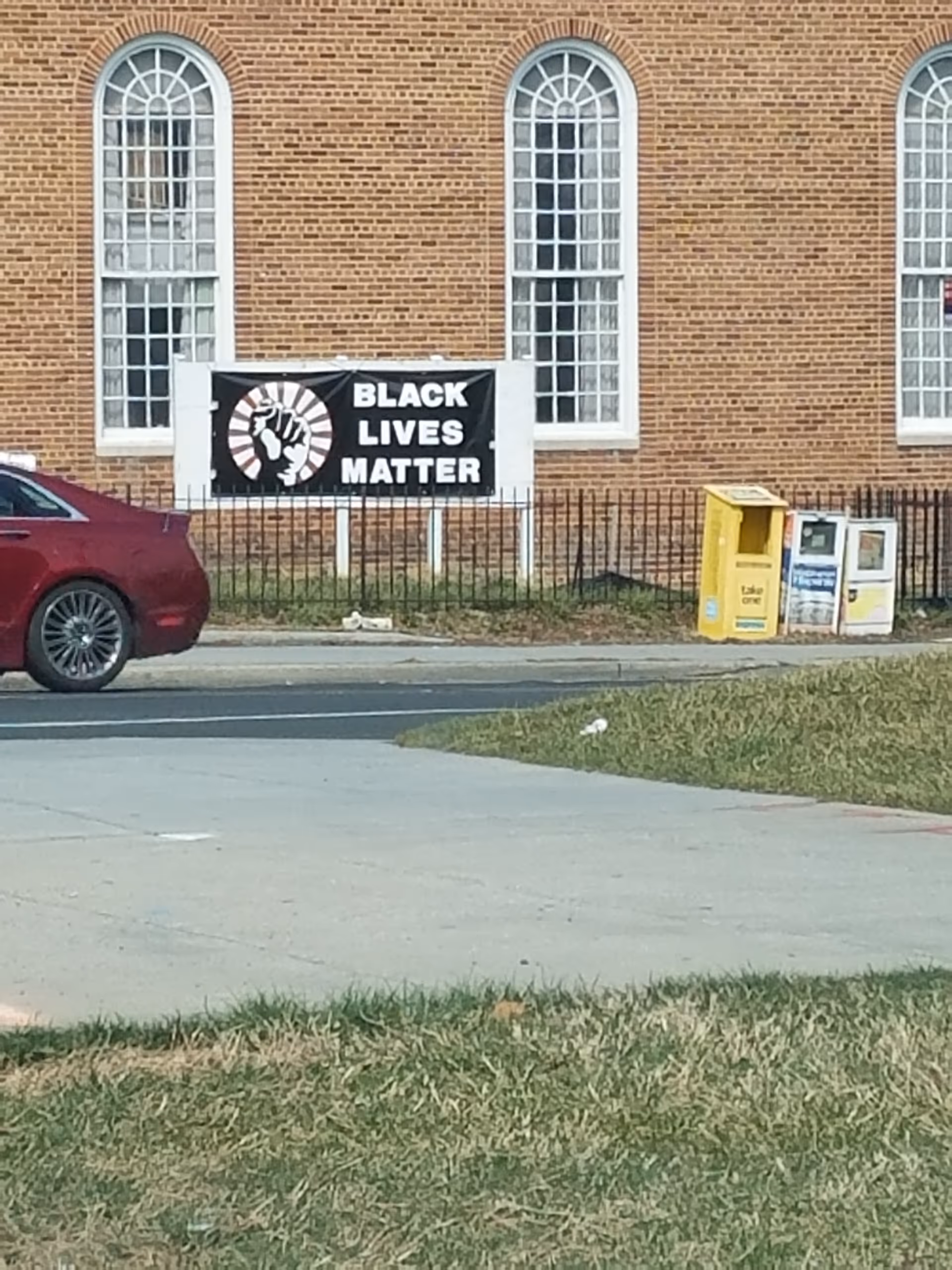 Exterior view of a brick building with arched windows and a Black Lives Matter banner.