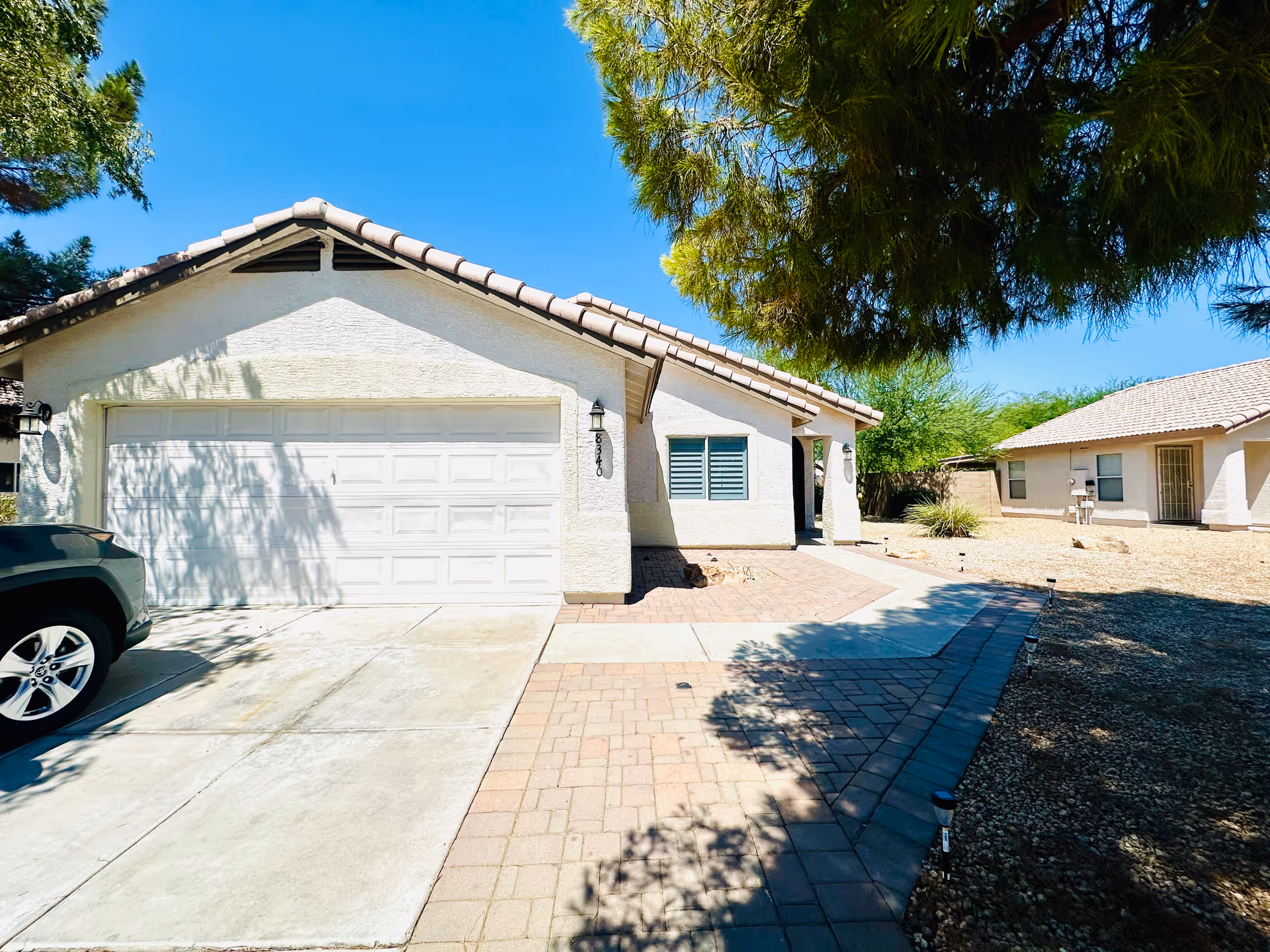 Front view of a beige single-story house with a two-car garage and desert landscaping.