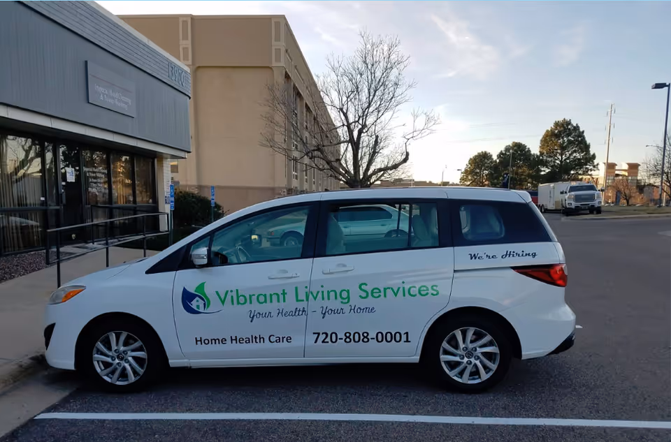 White Vibrant Living Services van with logo parked beside a building.
