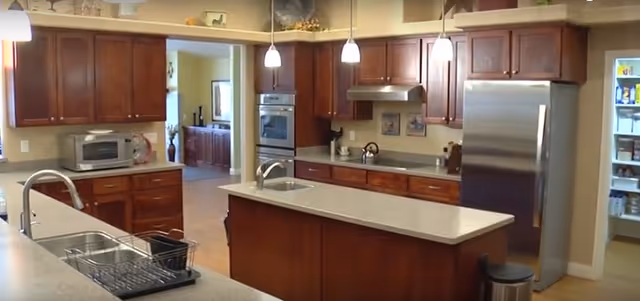 Spacious kitchen with dark wood cabinets, island sink, and stainless appliances.