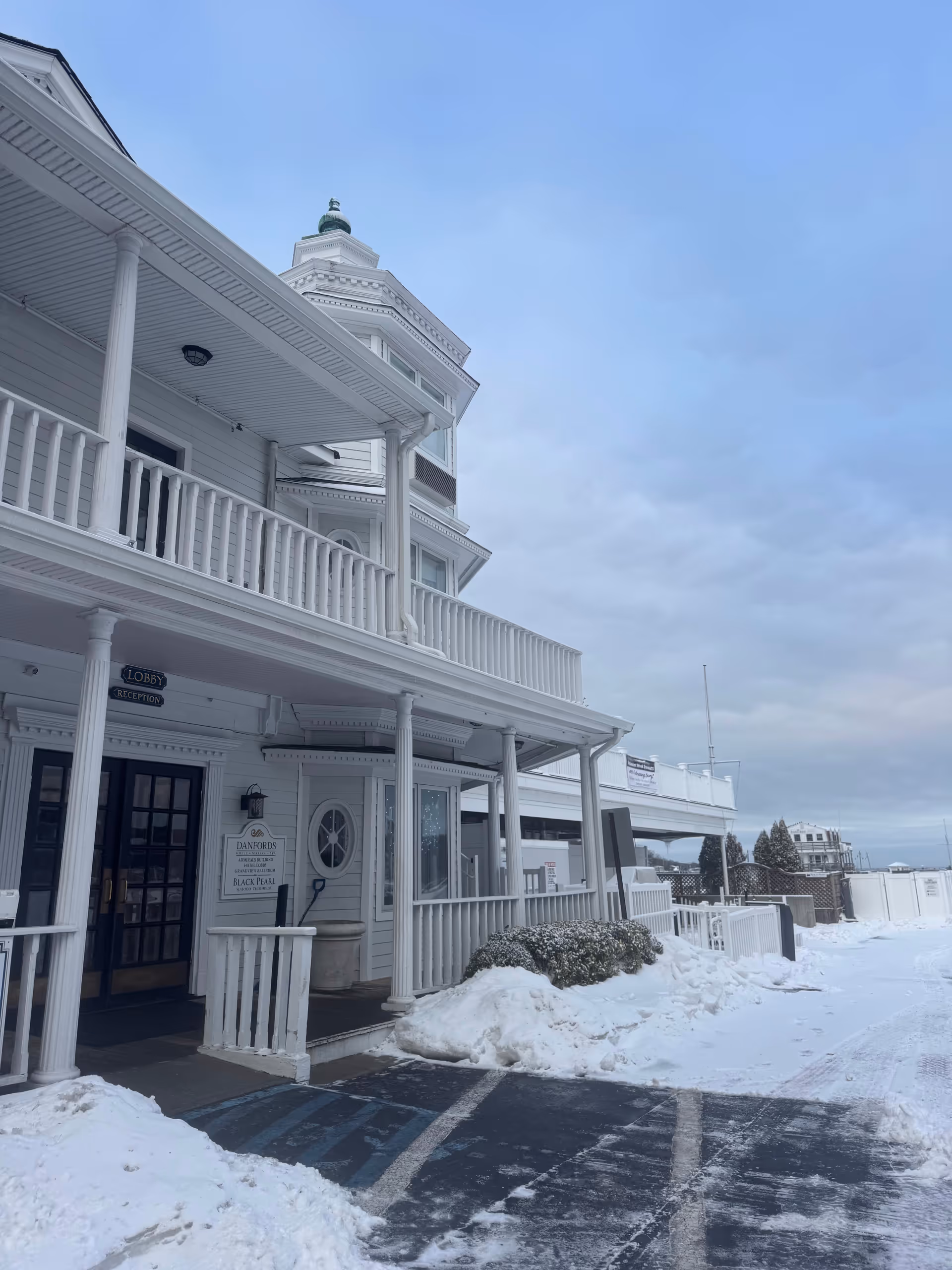 White Victorian-style building exterior with a wraparound porch and snow-covered ground.