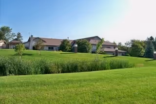 Sunny exterior view of Galeon senior living campus with green lawns.