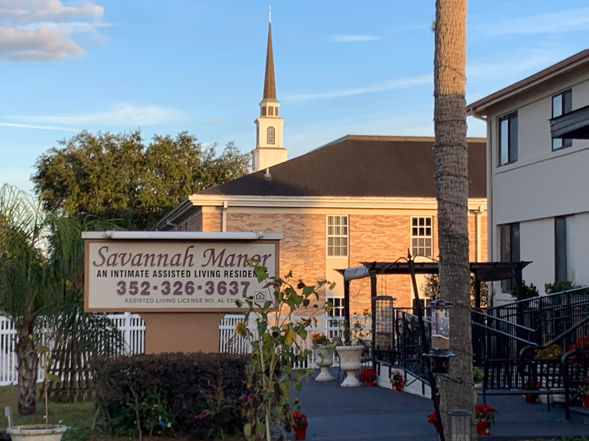 Savannah Manor sign in front of brick assisted living residence with outdoor seating.