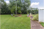 Outdoor lawn area at The Waters Of Springfield with a path, trees, and seating.
