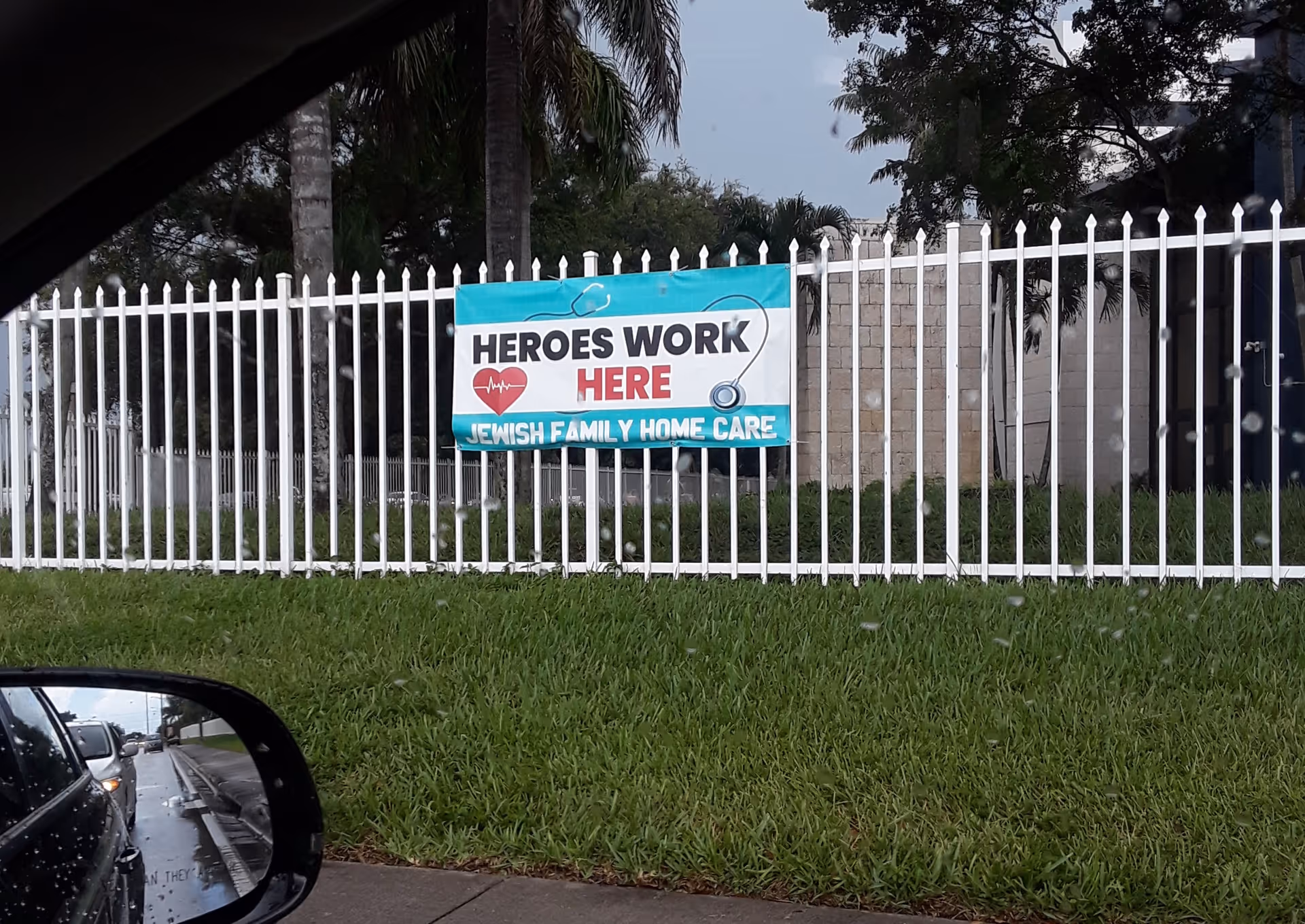 Banner on white fence reads Heroes Work Here for Jewish Family Home Care
