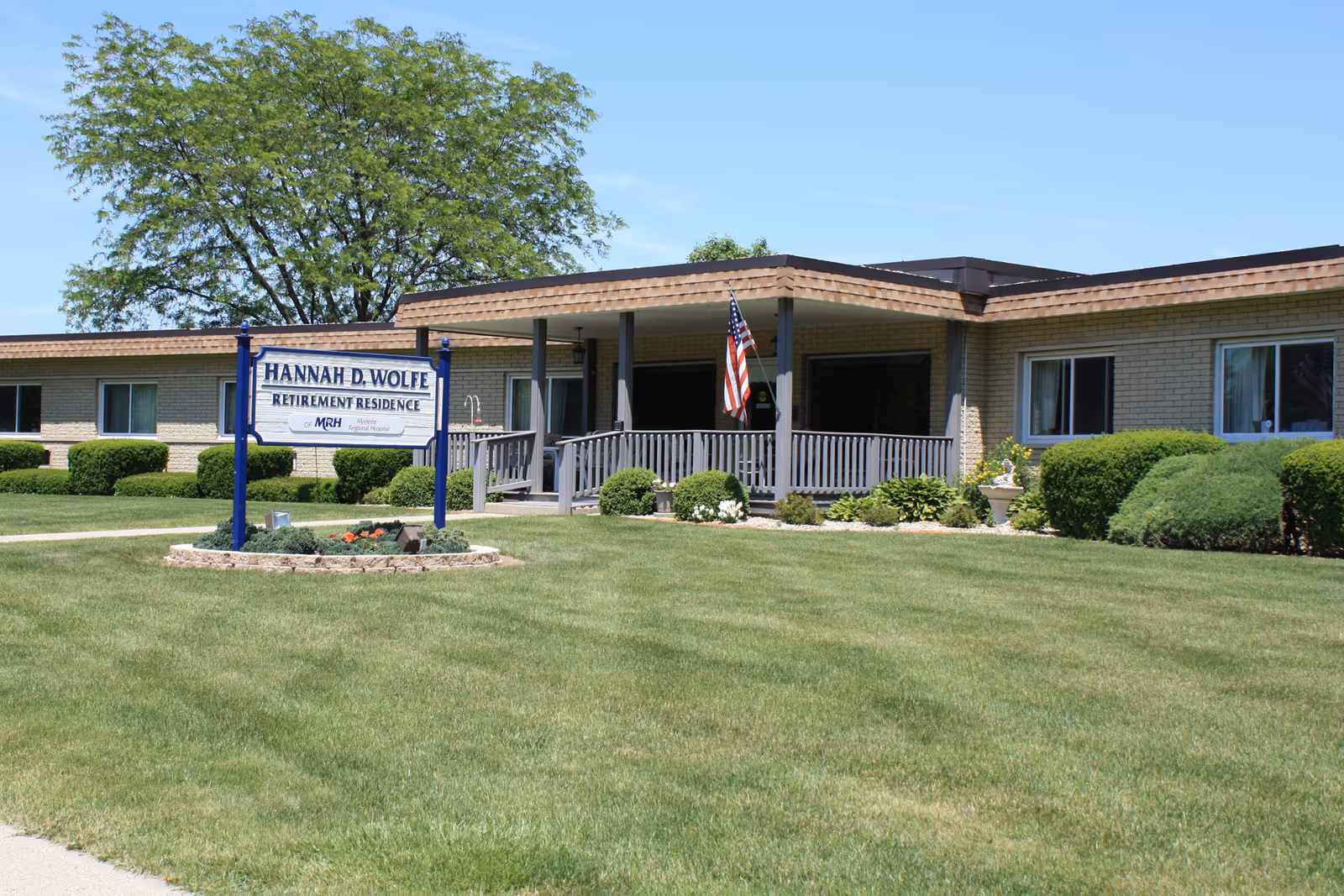 Front view of Hannah D Wolfe Retirement Residence with sign and manicured lawn