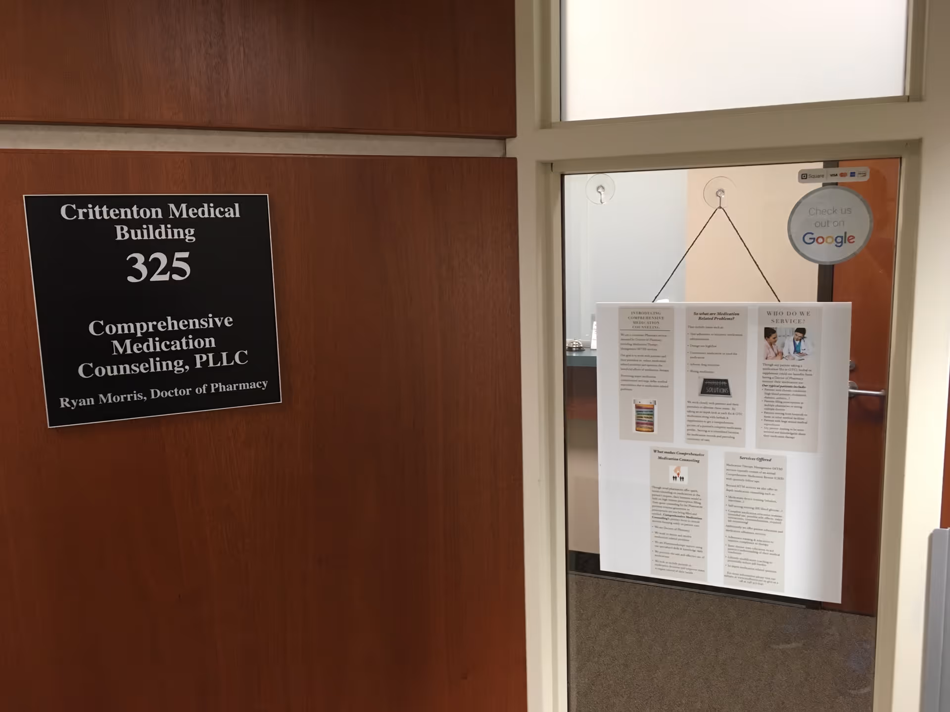 Wood-paneled hallway with a sign reading 'Crittenton Medical Building 325' and a glass door bulletin board.