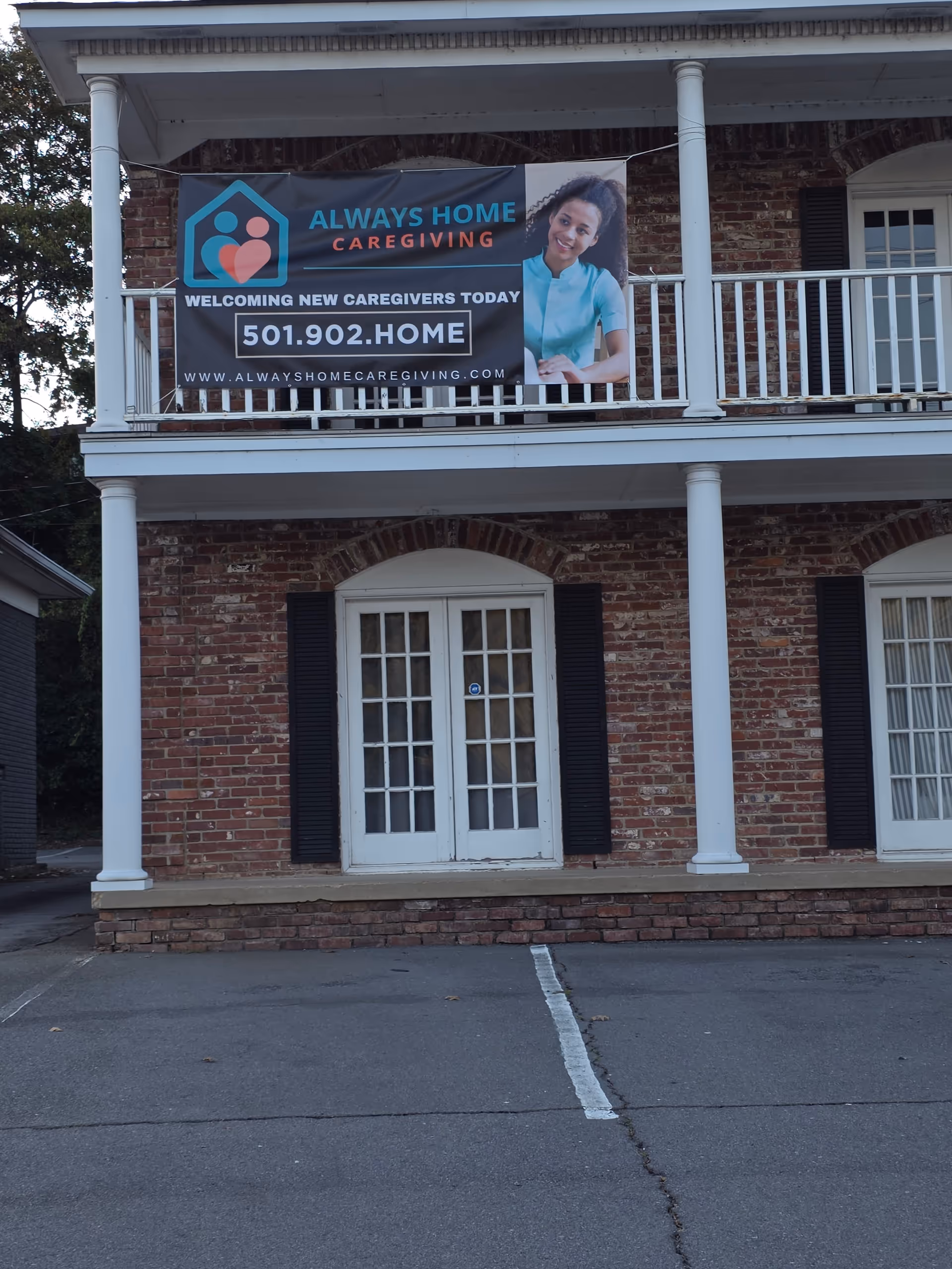 Front of a two-story brick building with an Always Home Caregiving banner.