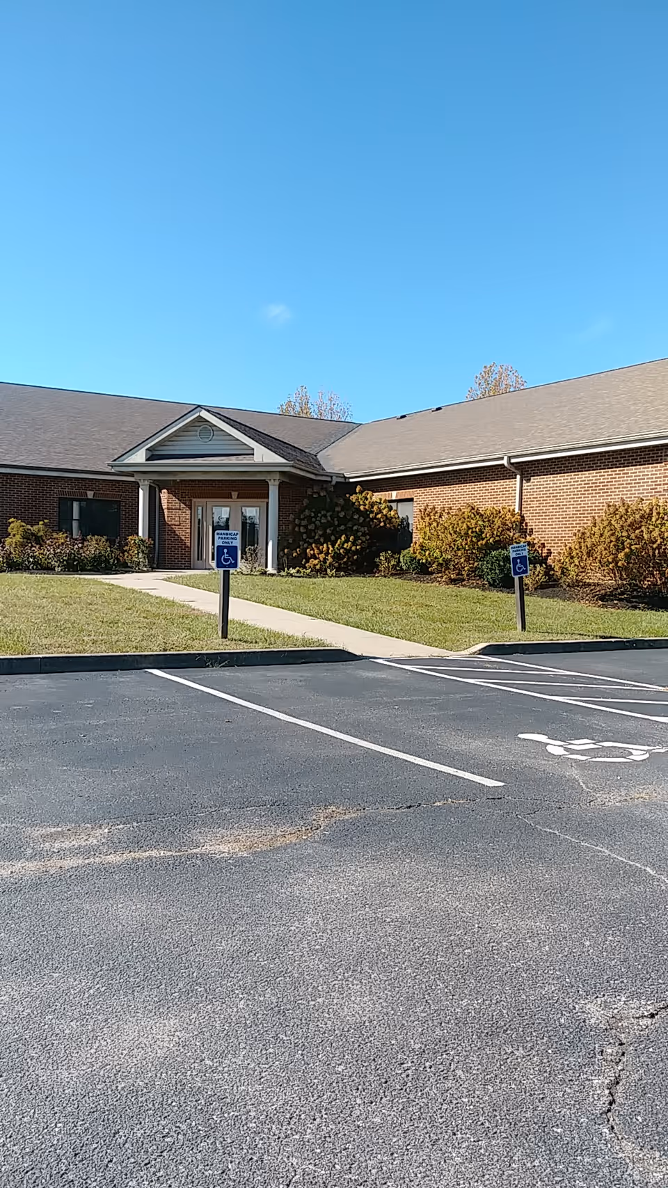 Front view of a brick senior living facility entrance with handicap parking.