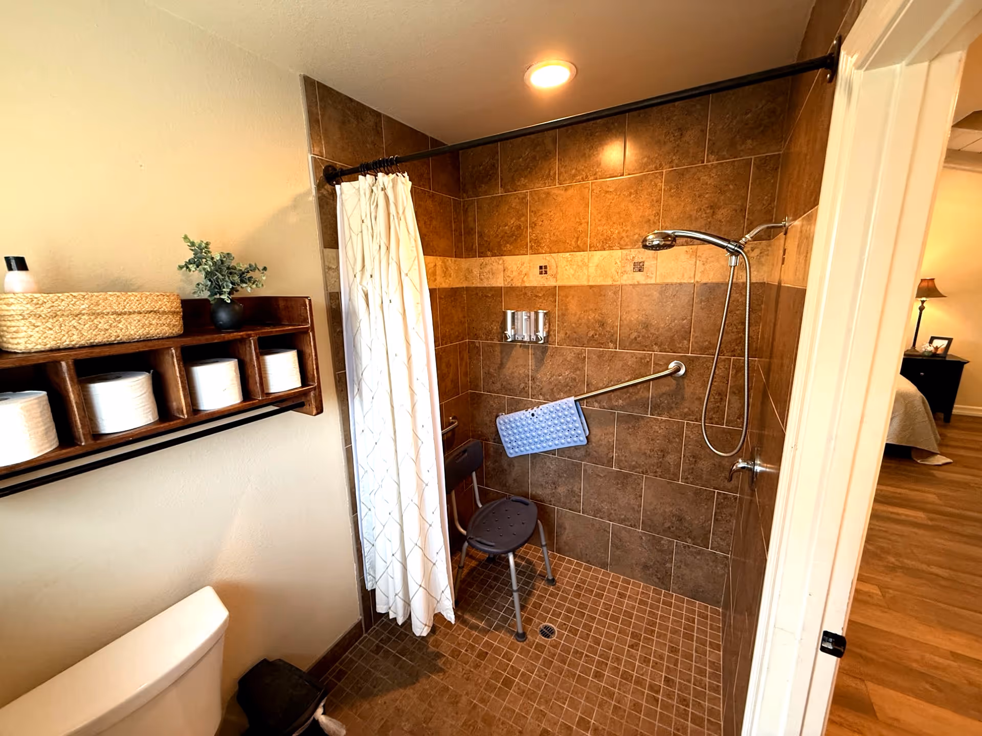Accessible bathroom with a tiled walk-in shower, grab bars, a shower chair, and storage.