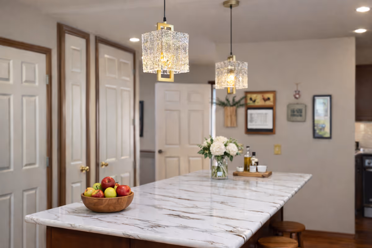 Marble kitchen island with fruit bowl, flower vase, and pendant lights.