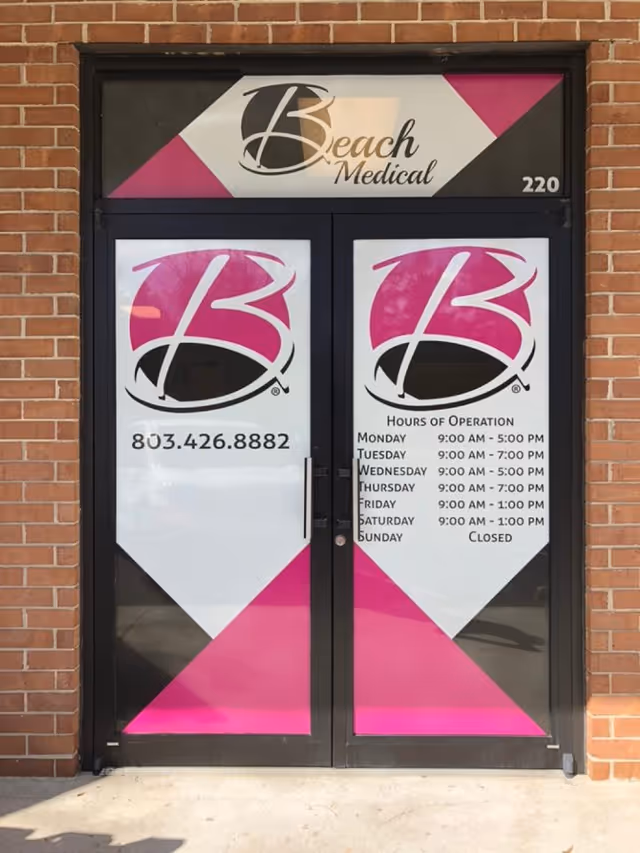 Brick building front with double glass doors and large pink and white signage