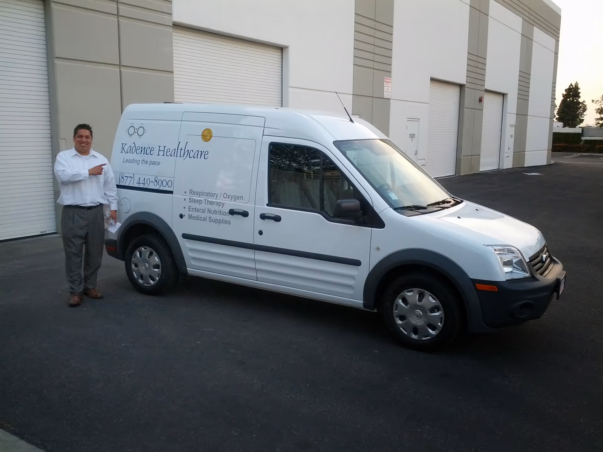 A Kadence Healthcare van is parked beside a building with a man pointing.
