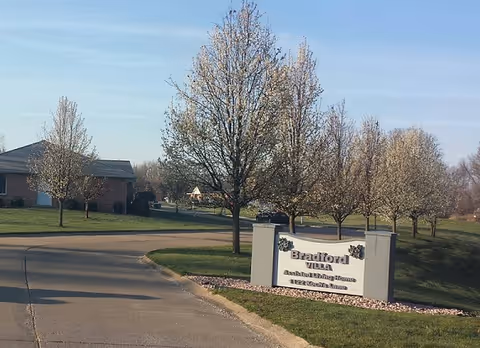 Entrance to Bradford Villas showing a curved driveway, sign, and blooming trees.
