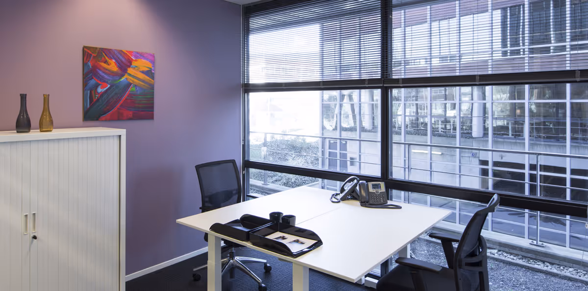 An office-style workspace in a senior living facility with a white desk and purple wall.