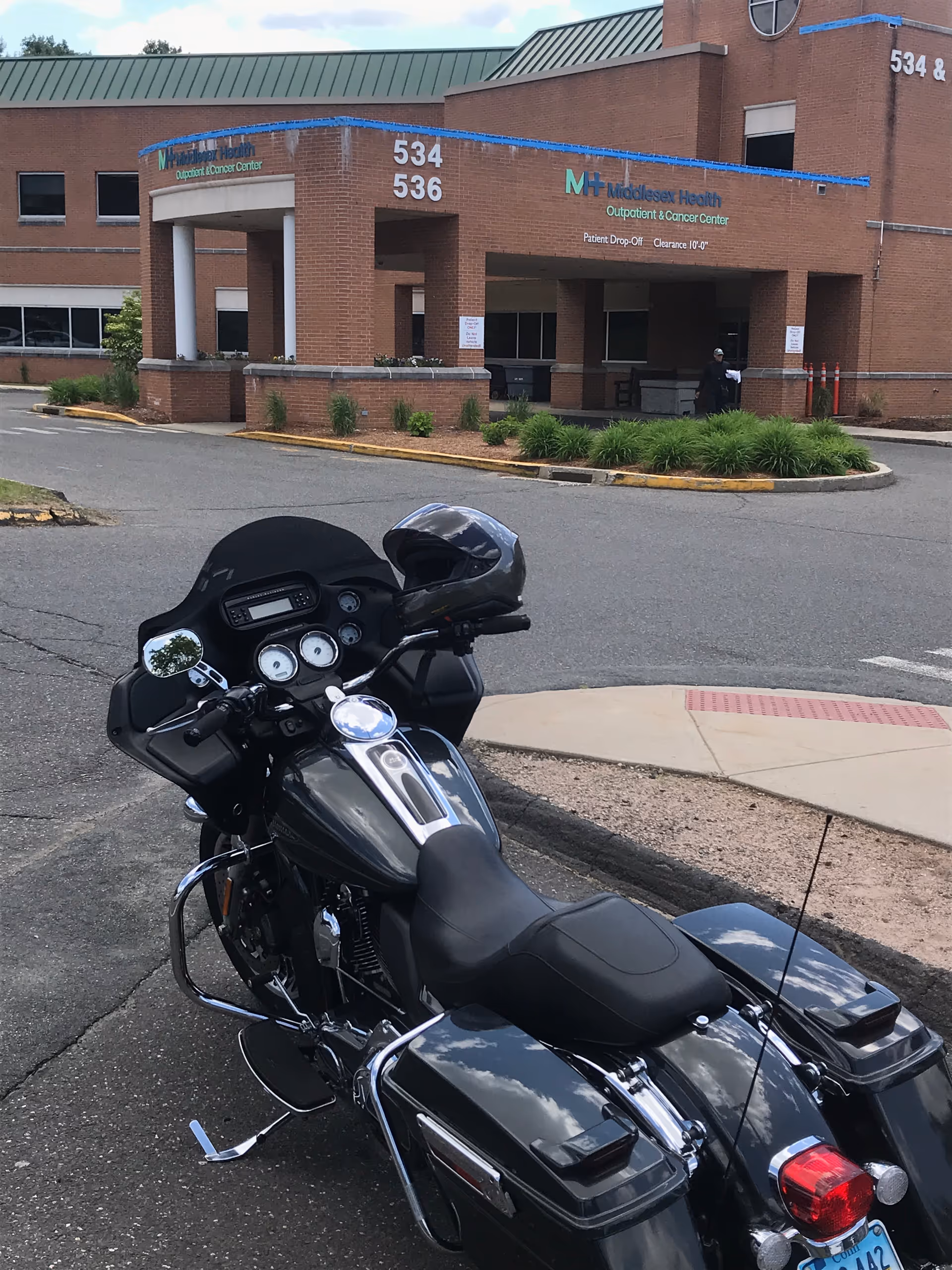 Brick medical center building with blue signage and a large black motorcycle parked outside.
