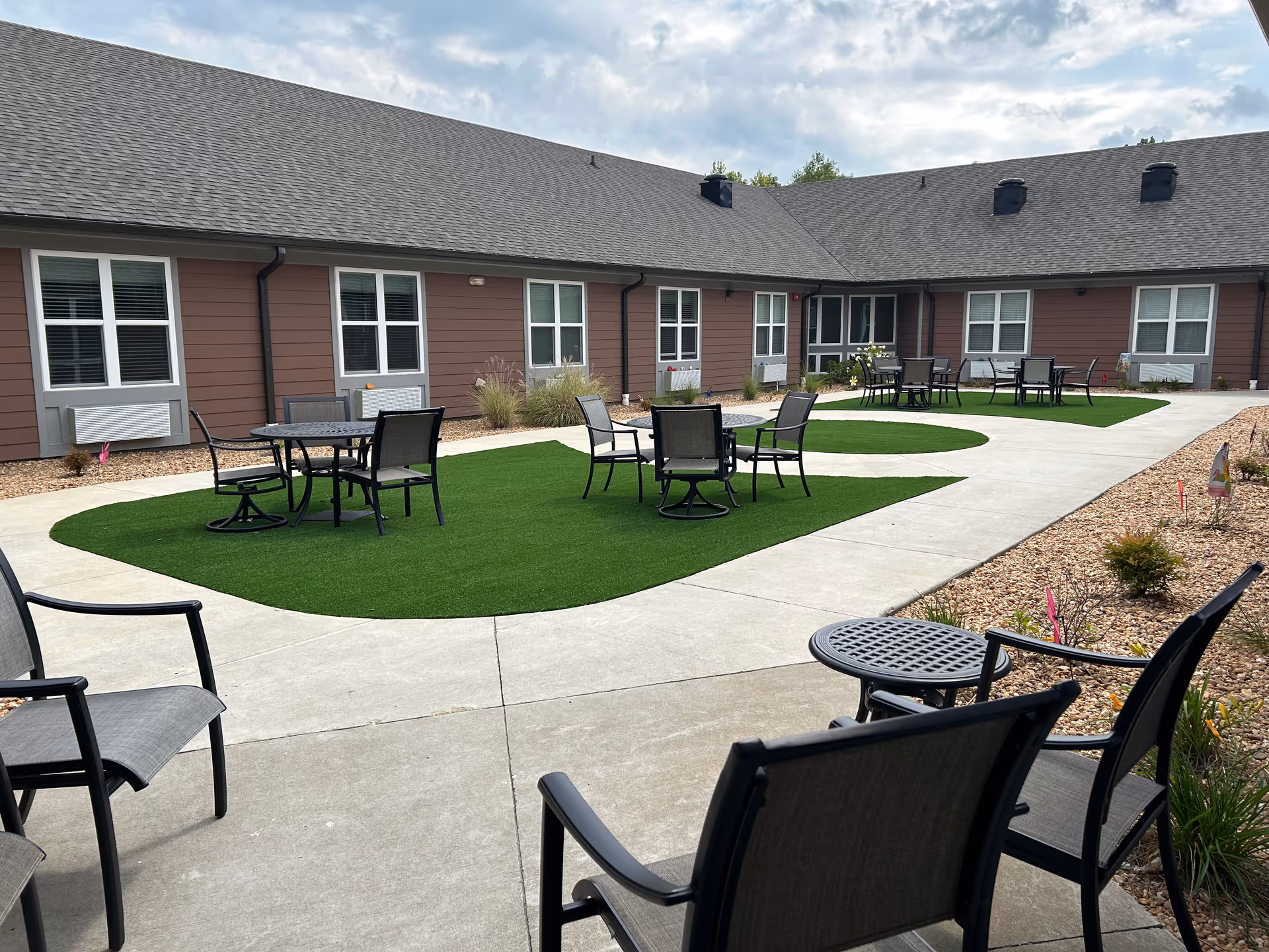 Outdoor courtyard with tables and chairs surrounding the brown building of The Drake.