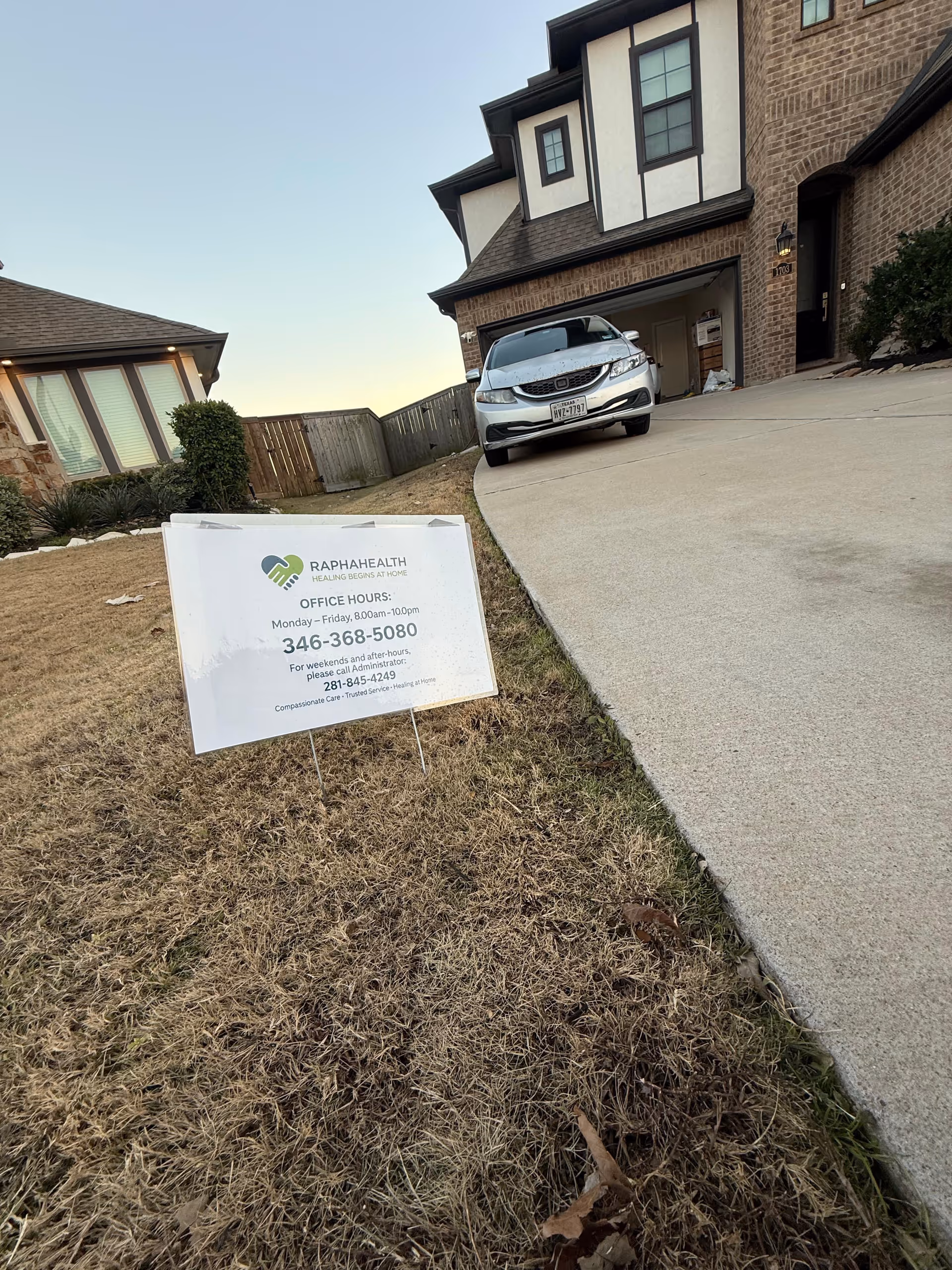 Front exterior of Rapha Health facility with sign, driveway, and a parked car.