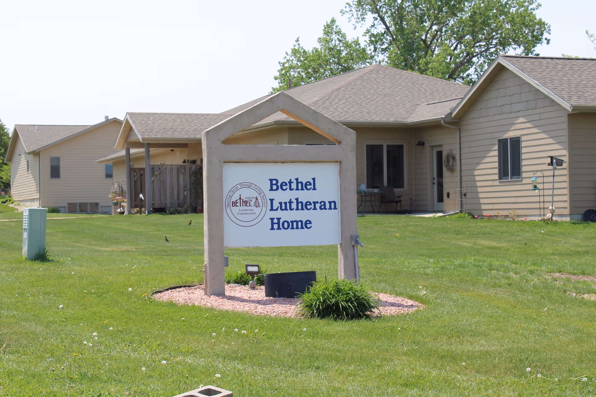 Front view of Bethel Lutheran Home sign and beige building on a green lawn