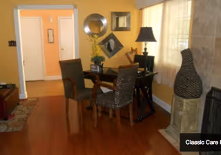 Warm interior dining area with a wooden floor, table, four chairs, and decorative mirrors.