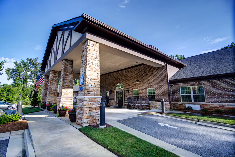 A brick senior living facility entrance with stone columns and a covered drop-off area.