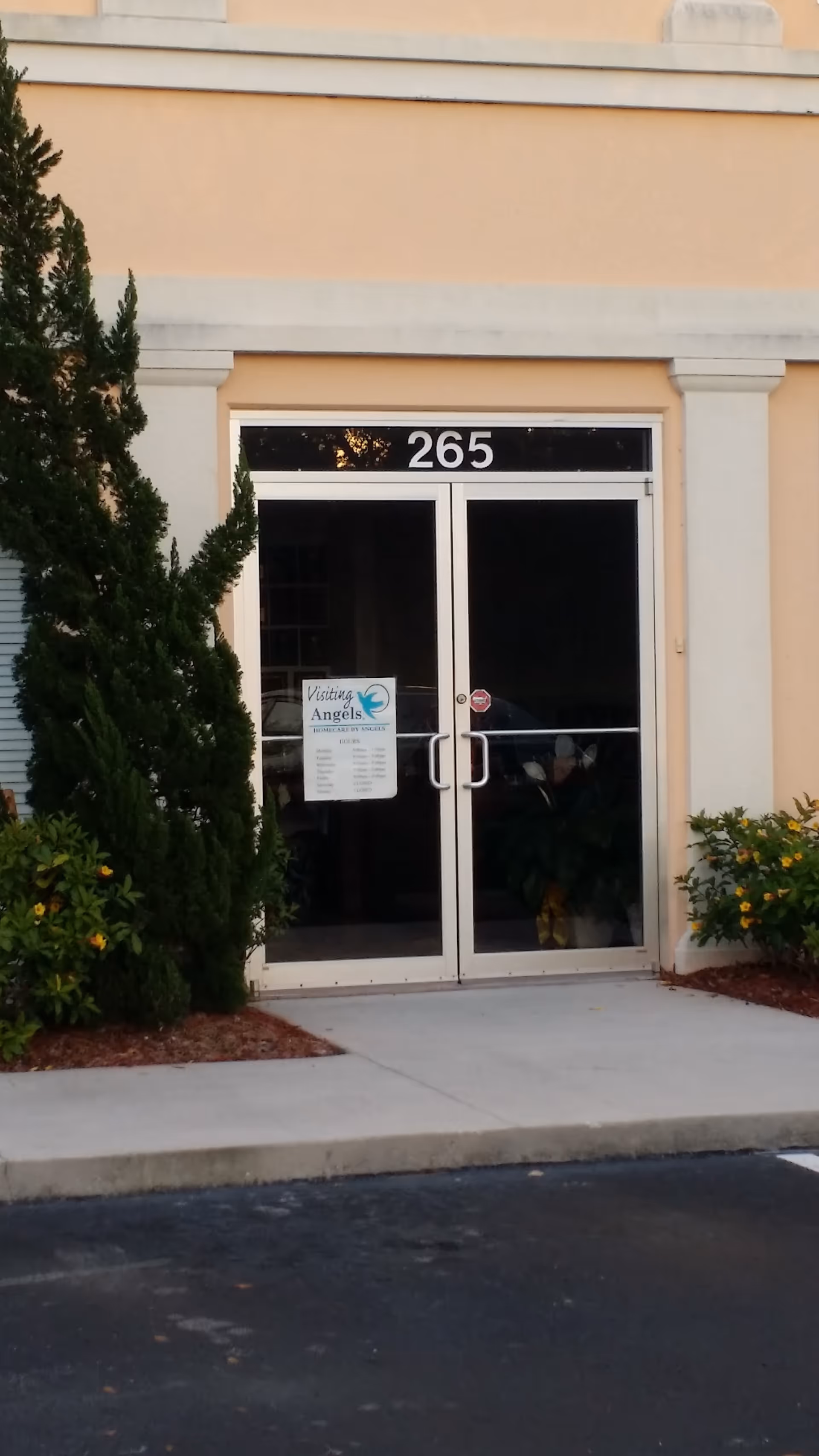 Entrance of Visiting Angels Senior Home Care Sanford with double glass doors and surrounding shrubs.