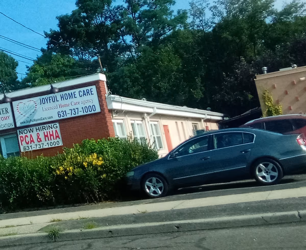 Exterior view of Joyful Home Care building with sign and parked cars.