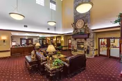 Spacious senior living lobby with stone fireplace, comfortable seating, and a front desk area.