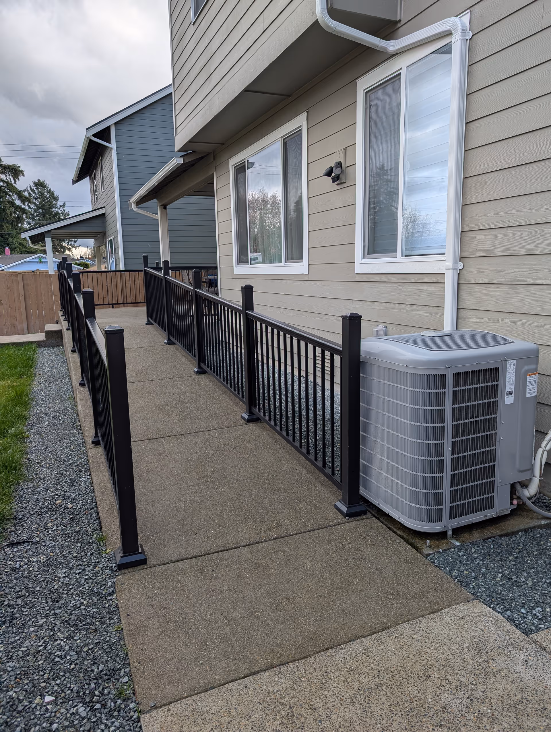 Exterior view of a beige senior living home with a ramp, railing, and air conditioner.