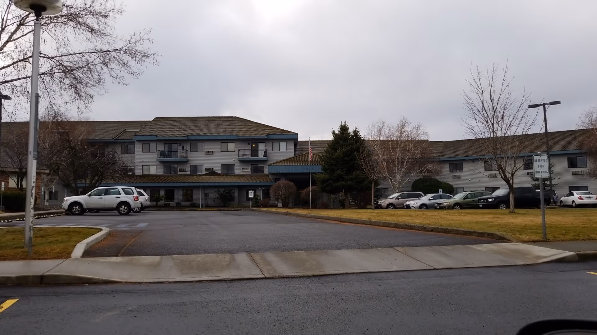 Exterior view of Evergreen Estates senior living building with a parking lot and leafless trees.