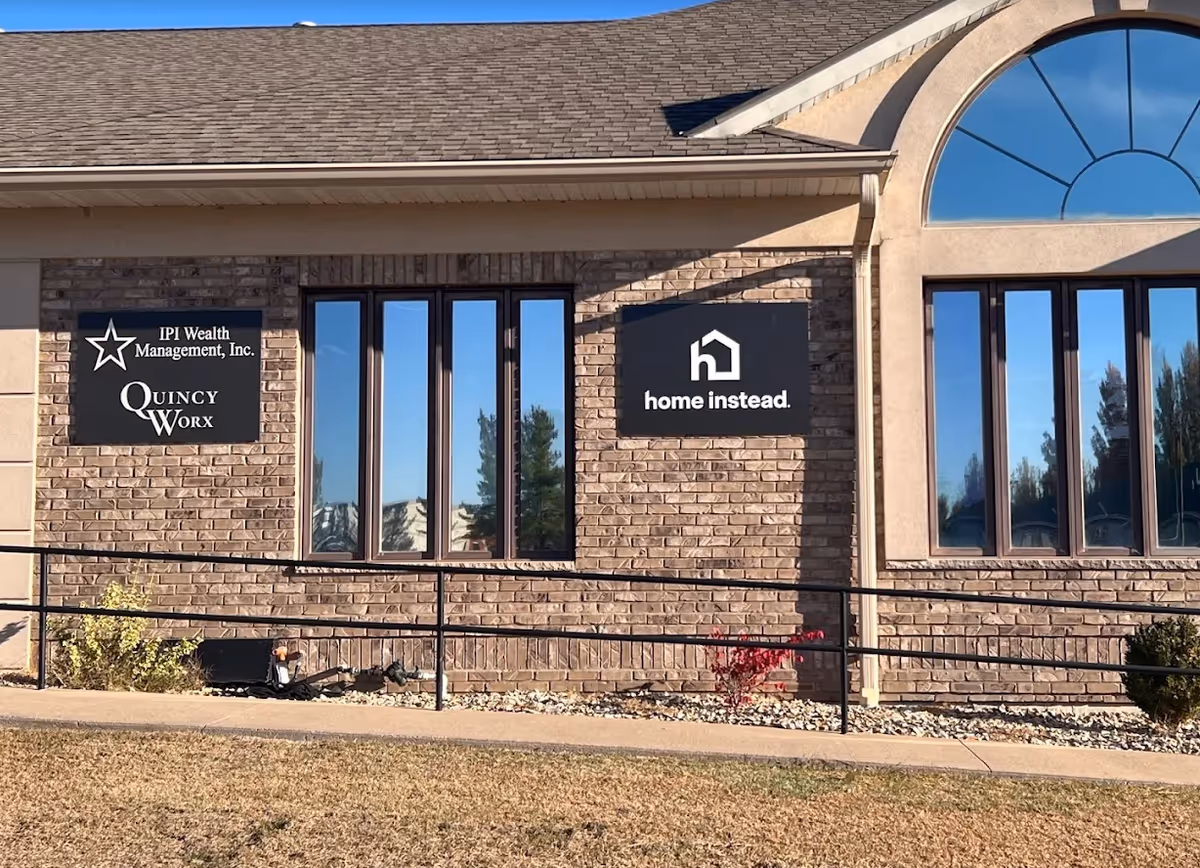 Brick building exterior features Home Instead and Quincy Worx signage.
