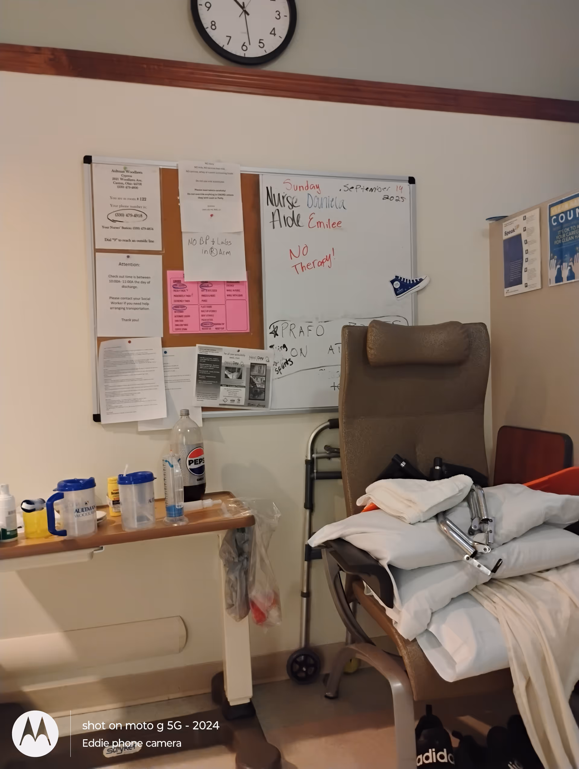 Treatment room corner with a recliner, whiteboard, and medical supplies.
