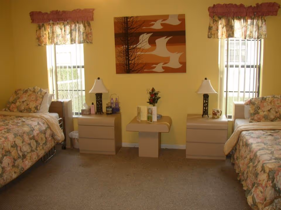 Two floral beds flank nightstands with lamps in a yellow bedroom.