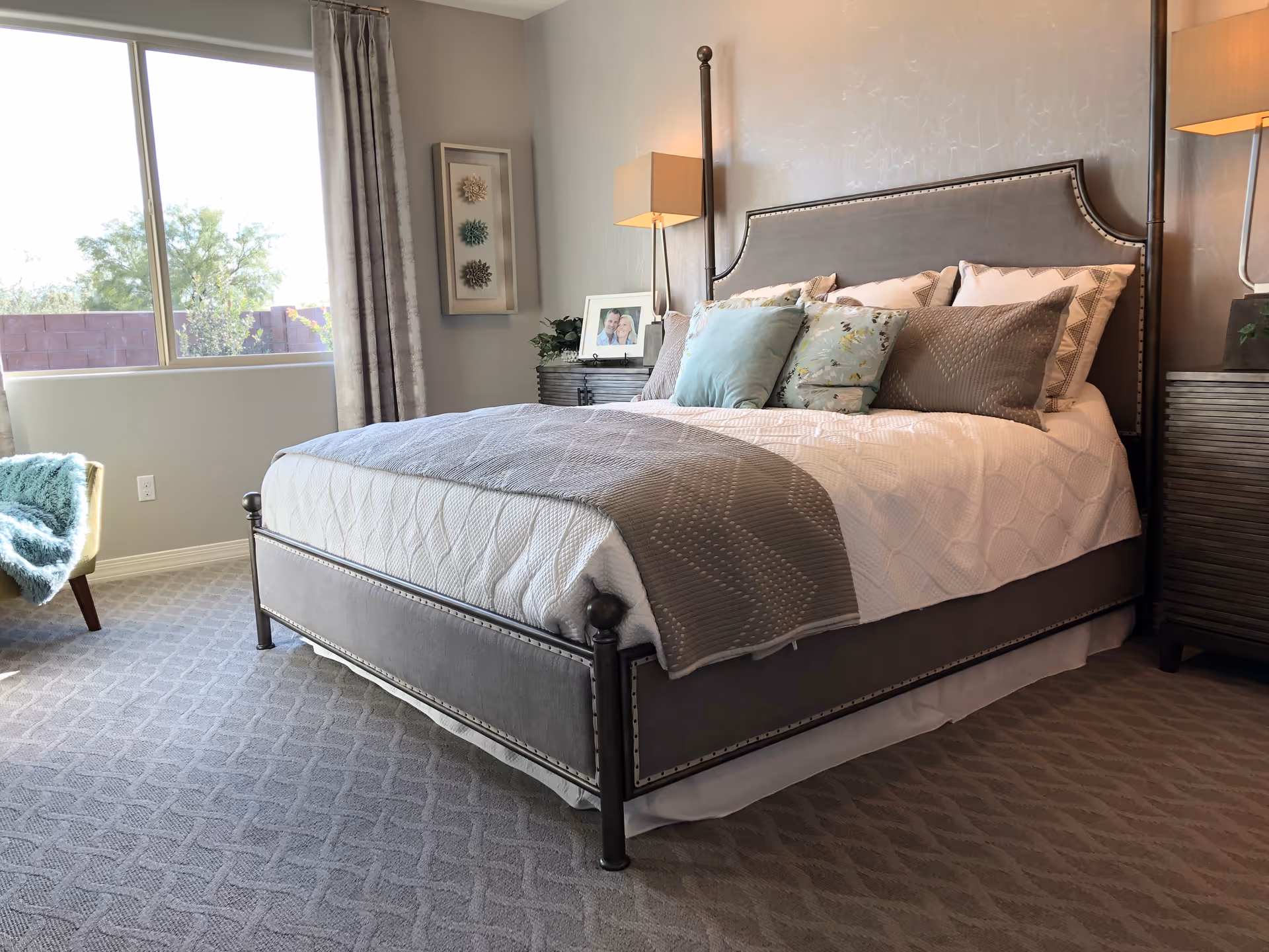 A neatly made gray-toned bedroom featuring a large bed, two nightstands, and a window.