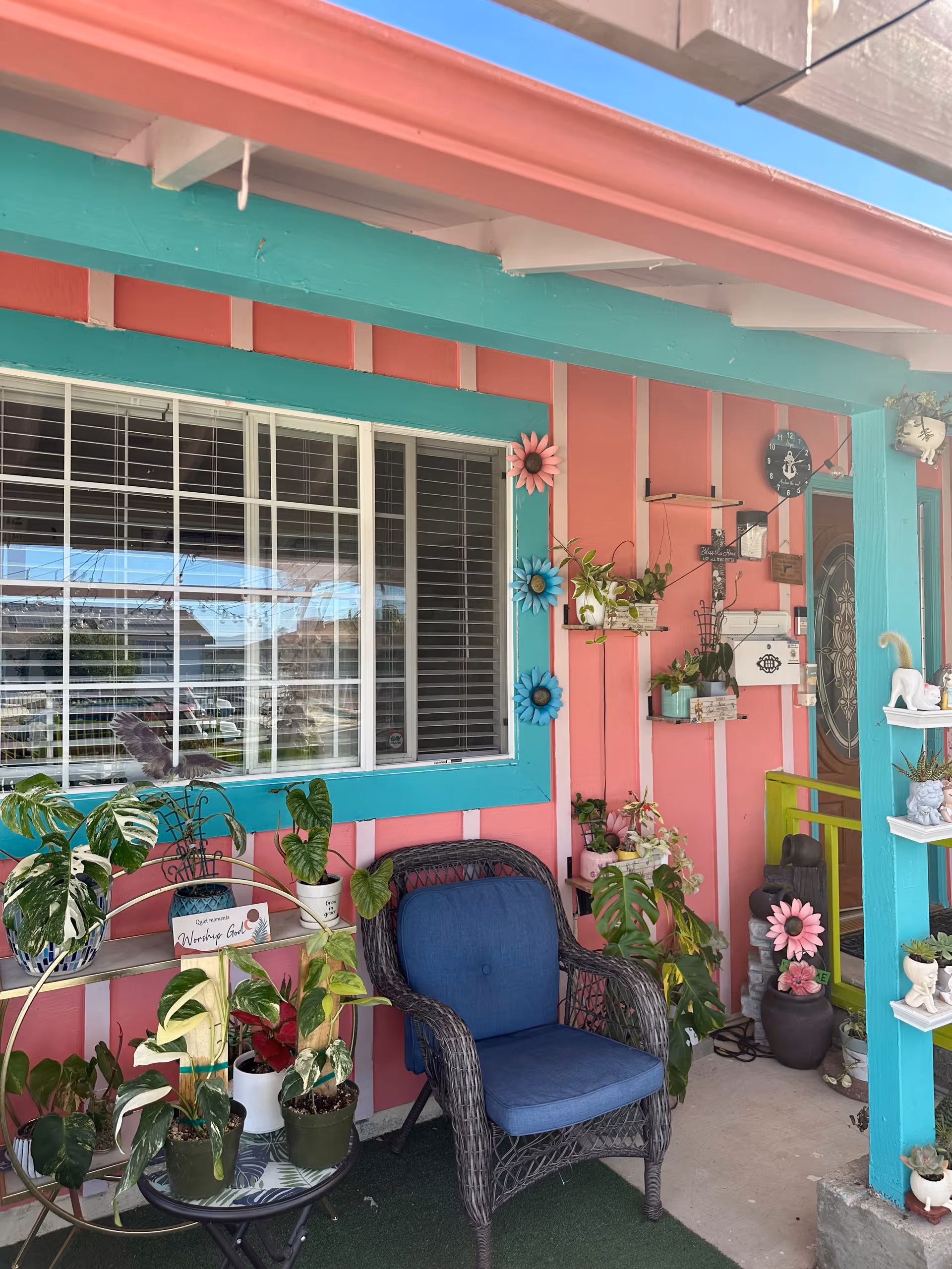 Colorful outdoor porch with a blue chair, plants, and decorative wall accents.