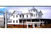 Exterior view of Goodwater Healthcare Center, a white multi-story facility with a wraparound porch.