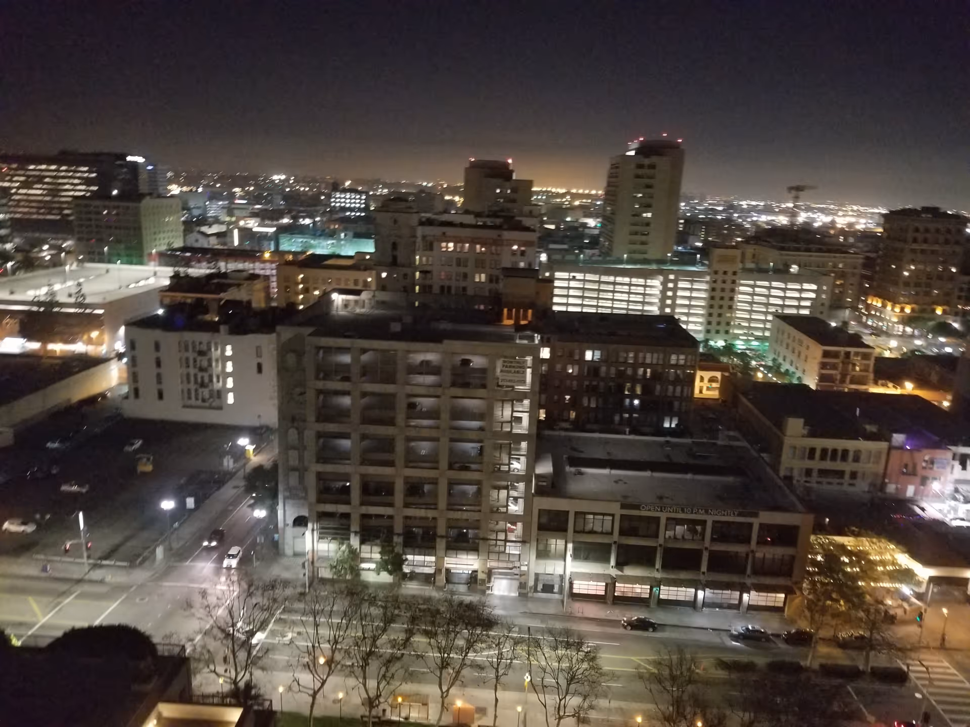Nighttime cityscape from a high vantage, showing illuminated streets and stacked buildings.