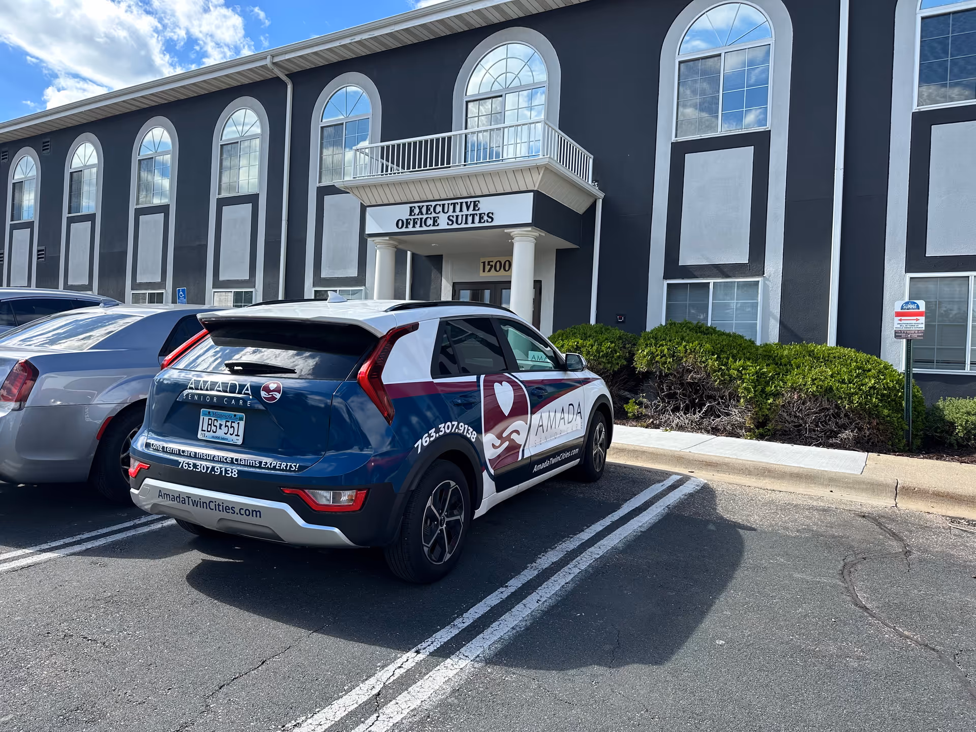 Exterior view of a dark building with arched windows and Amada Senior Care car.