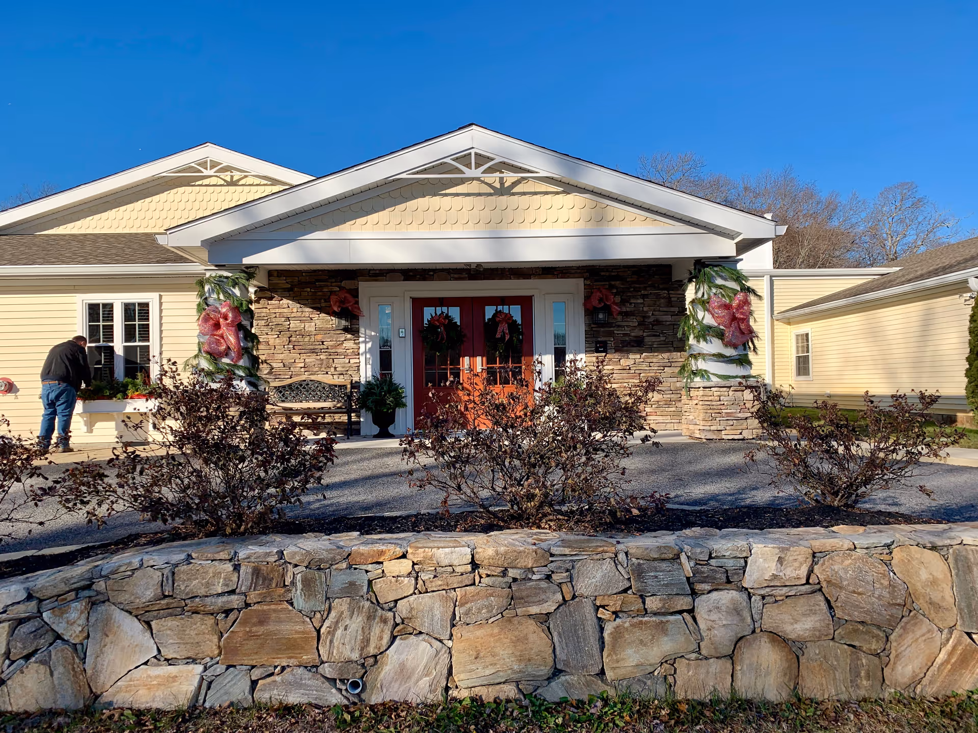 Exterior view of Briarcliffe Gardens Memory Care entrance with stone facade and wreaths.