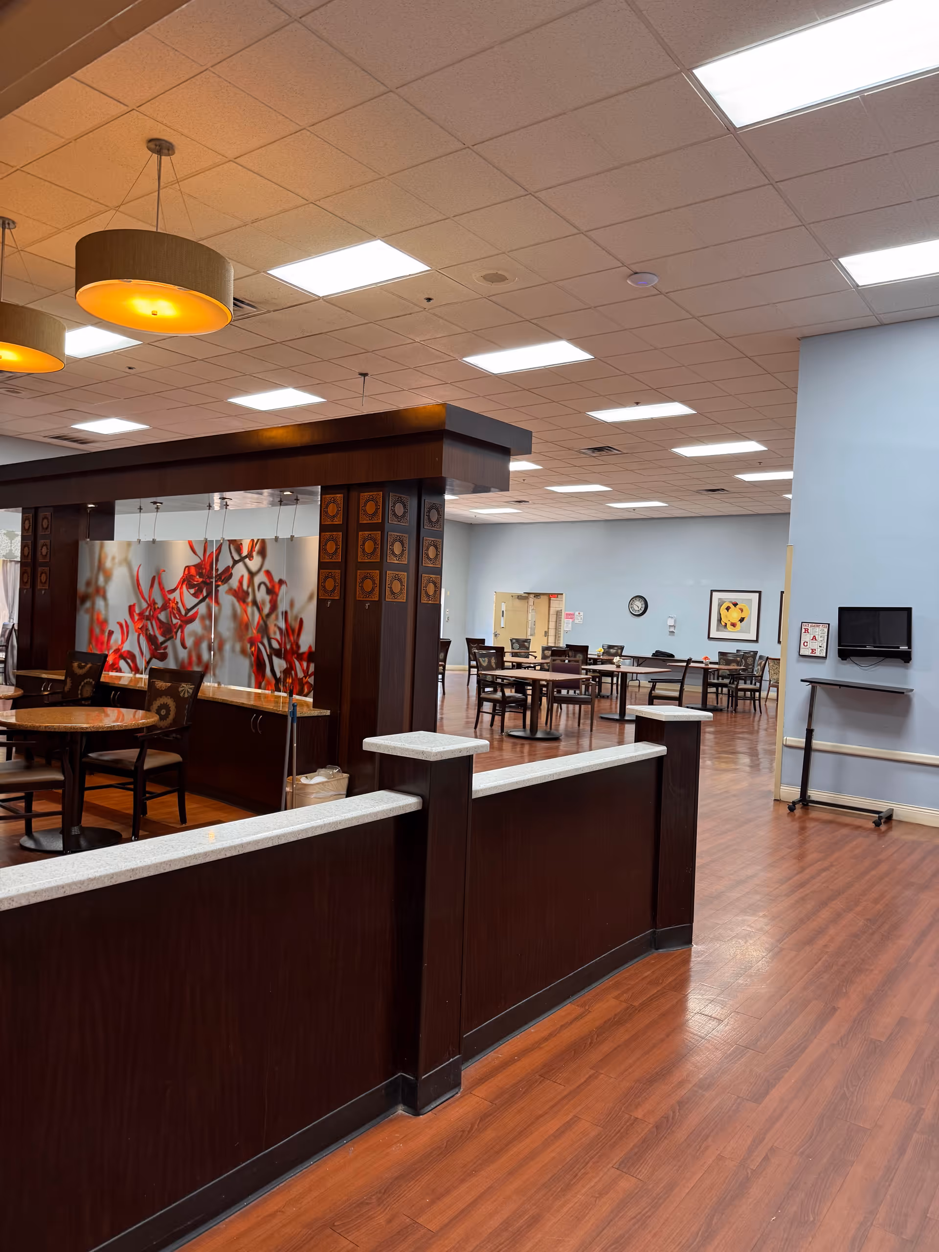 Interior dining area with dark wood partitions, tables, chairs, and warm ceiling lighting.