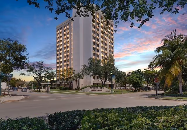 Tall multi-story senior living building with landscaping and a street sign reading Imperial Club.