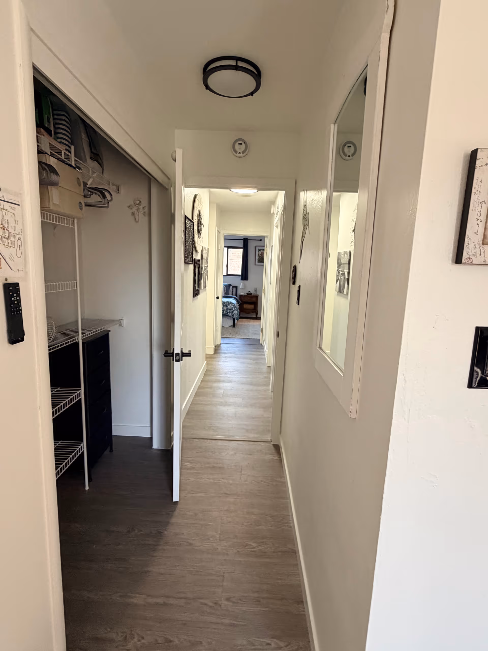 Narrow hallway in a senior living facility with open closet and distant bedroom.